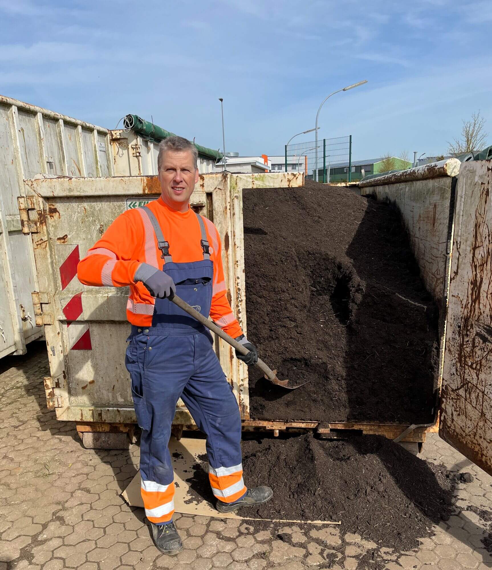 Bernd Westensee, ZVO Mitarbeiter, vor mit Kompost gefüllten Container stehend